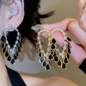 Macro shot of vintage hoop earrings with zircon accents and black teardrop tassels