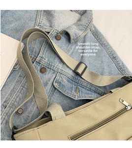 Detail of adjustable smooth shoulder strap and metal zipper on light khaki canvas bag
