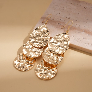 Gros plan détaillé des boucles d'oreilles goutte d'or avec texture martelée sur pierre