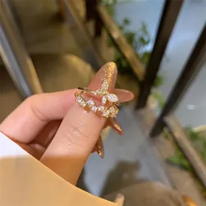 Gros plan d'une bague papillon dorée à double couche avec oxydes de zirconium au doigt
