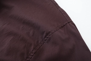 Macro detail of dark brown poplin fabric showing precise double-stitch seams and smooth texture