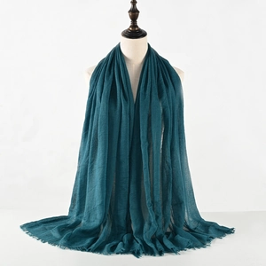 Dettaglio di sciarpa in cotone stropicciato verde scuro con frange su un manichino