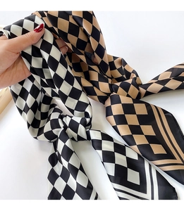 Close-up of black and khaki checkerboard silk scarves with a glossy finish texture