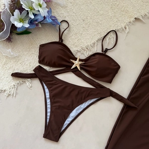 Détail d'un bikini marron foncé orné d'une étoile de mer dorée sur tapis texturé