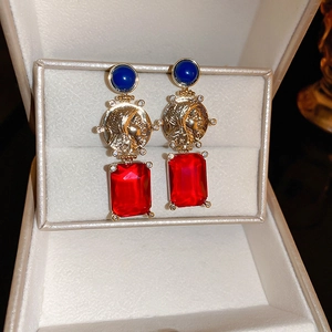 Detail of vintage coin earrings with blue round stones and red rectangular crystals
