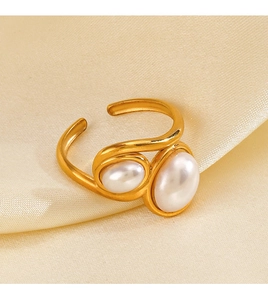 Macro detail of gold-plated open ring featuring two white pearls on silk background