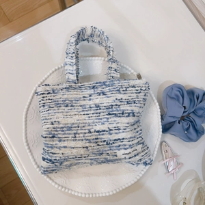 Mini borsa a mano in tweed arcobaleno con trama intrecciata e etichetta su piatto decorato