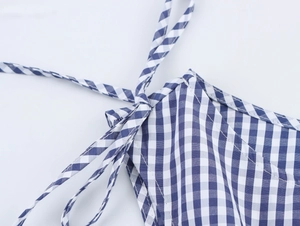 Detail of blue and white plaid dress showing shoulder tie-up design and cotton fabric texture