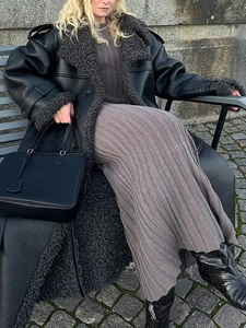 Close-up of black faux fur shearling coat with plush cuffs and leather texture finish