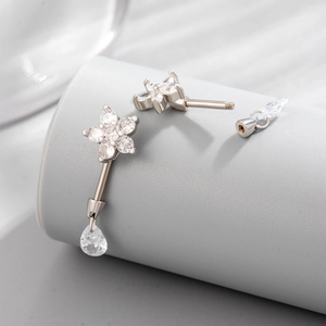 Silver steel flower piercing jewelry with drop pendant and zircon studs on display