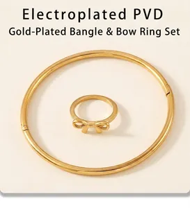 Detail view of gold PVD plated bow ring and minimalist bangle on stone texture