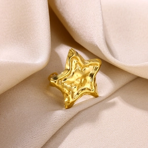 Macro shot of gold stainless steel star ring with textured hammered finish on satin cloth