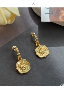 Close-up of matte gold sunflower earrings with sunburst relief and braided edges