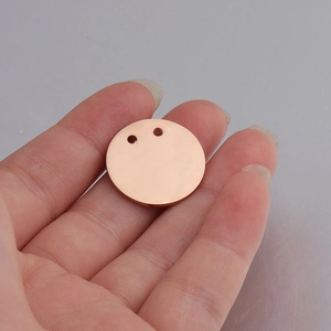 Close-up of 21mm rose gold round metal pendant with double holes on a palm for scale