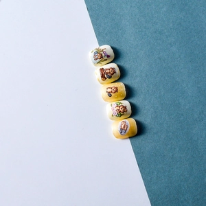 Macro view of five adhesive nail stickers featuring cute cartoon bears and flower patterns
