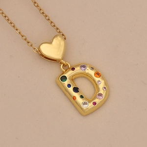 Macro shot of gold heart necklace with colorful zircon-encrusted letter D pendant