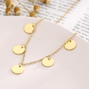 Detail of a gold stainless steel necklace with five round disk pendants on an O-chain