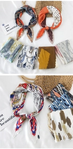 Detail of pleated silk scarf with chain print and wavy patterns on white bedding