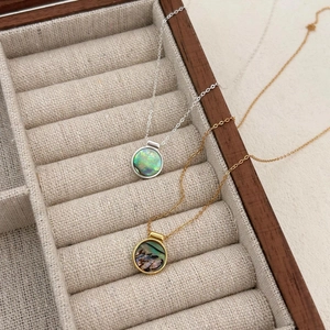 Detail of silver and gold abalone shell necklaces inside a rustic wooden jewelry box