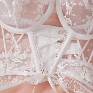 Detailed macro shot of white floral lace embroidery and satin ribbon lacing on lingerie
