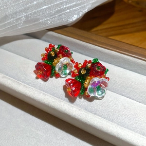 Detail view of handmade beaded floral earrings with red and green crystal clusters