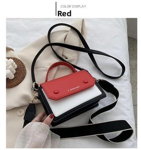 Detail of red contrast shoulder bag with black and white stripes strap on white bedding