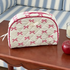 Detailed view of quilted bow cosmetic bag on wooden table with elegant ribbon