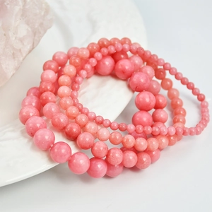 Pink rhodochrosite beaded bracelets set with various bead sizes on white porcelain plate