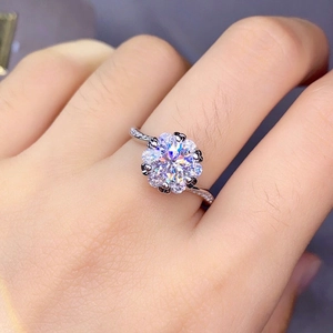 Detailed close-up of a floral pavé diamond ring in silver setting on a finger