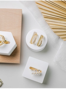 Flat lay of gold rings with pearls and zircons on white plaster props and wooden board