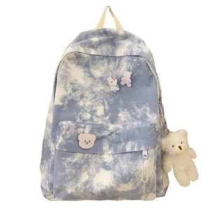 Detail of blue tie-dye canvas backpack with cute bear pendant and decorative pins