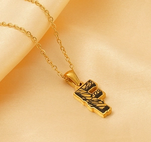 Detail of 18k gold-plated necklace with letter E pendant and black enamel pattern