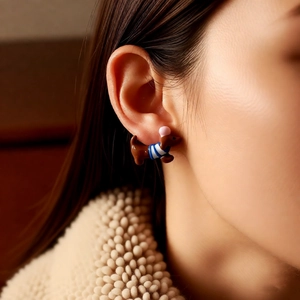 Detailansicht eines süßen Dackel-Ohrsteckers mit blauen Streifen am Ohr eines Models