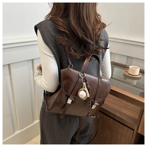 Détail du sac à dos marron foncé avec boucles vintage et pendentif de baseball