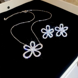 Macro detail of silver floral pendant and earrings set with shimmering crystals