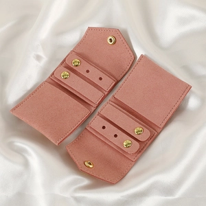 Detailed view of two pink microfiber jewelry pouches with gold snaps on white silk fabric