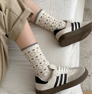 Detail of beige cotton socks featuring brown circular patterns and gray ribbed cuffs