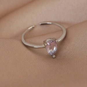 Macro detail of silver open ring featuring a teardrop pink gemstone on silk
