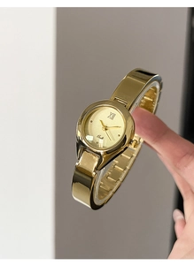 Close-up of Gedi gold bangle watch featuring a Roman numeral dial and polished metal band