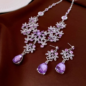 Detailed macro view of vintage floral jewelry set with purple crystals on brown fabric