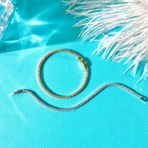 Elegant 2mm tennis bracelet with gold and silver finishes on a textured blue background