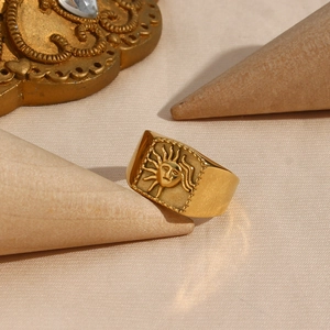 Macro detail of a gold plated stainless steel signet ring with a sun face relief design