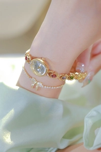 Close-up of golden bracelet watch featuring rainbow gemstones on a woman wrist