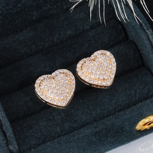 Macro view of heart stud earrings with pave-set zircons on green velvet box