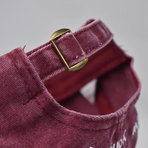 Detail of vintage burgundy washed cotton baseball cap with adjustable bronze metal buckle