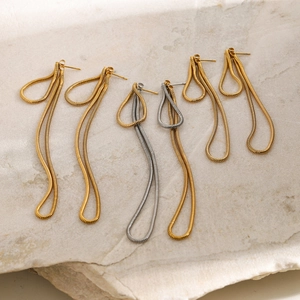 Detail of 18k gold and silver snake chain fringe earrings on natural stone surface