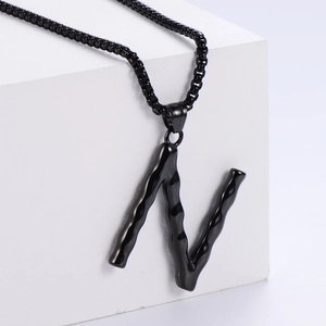 Vue détaillée du pendentif lettre N noir avec une texture de lave irrégulière