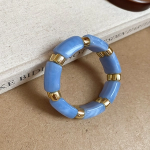 Detail of light blue marble acrylic beads and gold metal spacers on a minimalist bangle