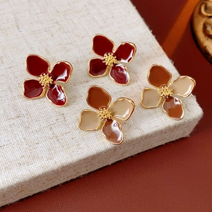 Detailed shot of vintage floral enamel earrings in red and brown on linen background