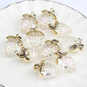 Translucent iridescent strawberry charms with gold leaves in a white ceramic dish
